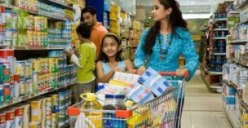 Mother with daughter holding shopping cart while father with son standing in background